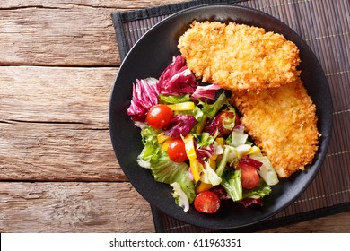 Chicken steak in breading Panko and fresh salad close-up on the table. horizontal view from above