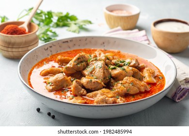 Chicken stew with paprika, onion and sour cream in plate on concrete background. Traditional Hungarian dish Paprikash. Selective focus.