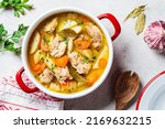 Chicken stew with potato and carrot in red pot, top view, copy space. Chicken soup with vegetables and herbs. Comfort food recipe.