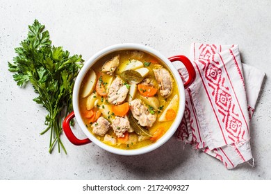 Chicken stew with potato and carrot in red pot, top view, copy space. Chicken soup with vegetables and herbs. Comfort food recipe.