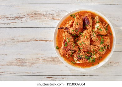 Chicken Stewed In Creamy Spicy Coconut Gravy, Kuku Paka, Served On A White Plate On An Old Wooden Table, View From Above, Close-up, Copy Space