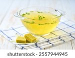 Chicken stock concentrate cube with ready to eat bouillon in a bowl on a kitchen table .