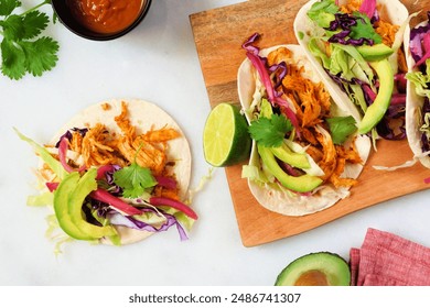 Chicken street tacos with avocado, cabbage slaw and pickled red onions. Overhead view table scene on a white marble background. - Powered by Shutterstock