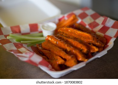 Chicken Strips Dipped In Buffalo Sauce Inside A Plastic Tray