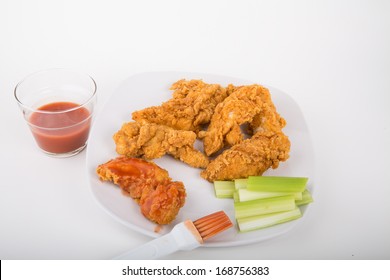 Chicken Strips On A White Plate With Buffalo Hot Sauce And Celery Strips