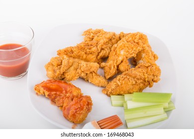 Chicken Strips On A White Plate With Buffalo Hot Sauce And Celery Strips