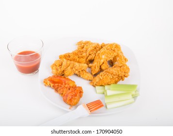 Chicken Strips On A White Plate With Buffalo Hot Sauce And Celery Strips