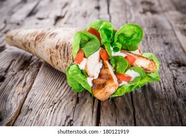 Chicken strips in Tortilla wrap on wood background.