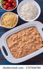 Chicken stroganoff accompanied with rice, salad and potato straw. Top view.