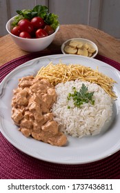 Chicken stroganoff accompanied with rice, salad and potato straw.