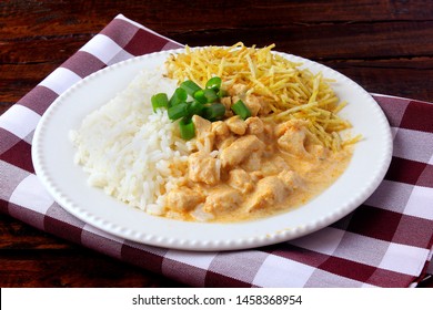 Chicken stroganoff, is a dish originating from Russian cuisine that in Brazil is composed of sour cream with tomato extract, rice and potato chips, on rustic wooden table.