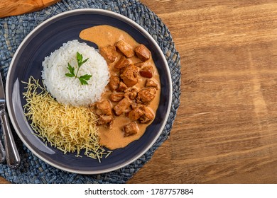 Chicken stroganoff with rice and french fries on a plate, over rustic wooden table. Top view. Space for text.