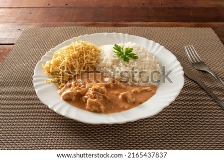 Chicken strogonoff accompanied with rice, salad and potato straw.