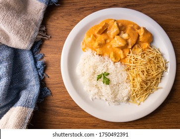 Chicken strogonoff with rice and french fries (potato sticks) on dish. 