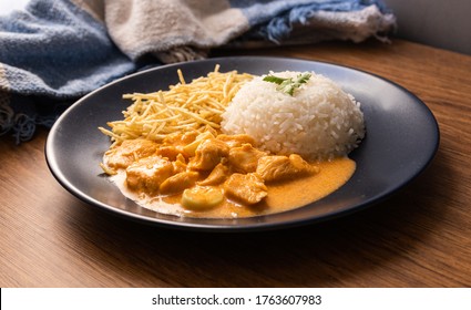 Chicken strogonoff with rice and french fries (potato sticks) on dish. Chicken stroganoff, is a dish originating from Russian cuisine.