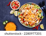 Chicken taco salad with tomatoes, cheese and black beans. Mexican food dish. Top view table scene on a dark background.