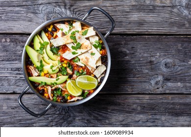 Chicken Taco Soup With Black Bean, Corn Kernels, Topped With Tortilla Strips, Avocado Slices And Lime In A Metal Pot On A Rustic Wooden Table, Flat Lay, Free Space