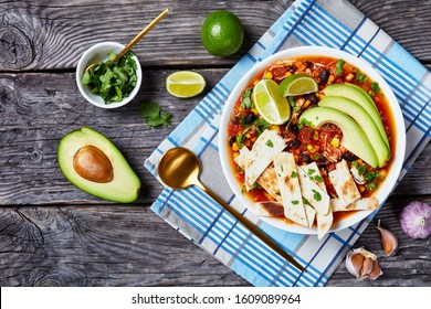 Chicken Taco Soup With Black Bean, Corn Kernels, Topped With Tortilla Strips, Avocado Slices And Lime In White Bowl On A Rustic Wooden Table, Horizontal View From Above, Flat Lay, Copy Space