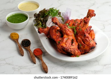 Chicken Tandoori Legs with Chutneys, Salad and Spices in spoons