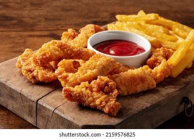 Chicken tenders, battered and fried crispy wedges, with a bbq sauce and potato, on a dark rustic wooden table - Shutterstock ID 2159576825