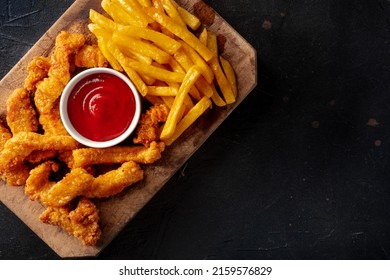 Chicken tenders, battered and fried crispy wedges, with a bbq sauce and potato, on a black slate background, top shot with copy space - Powered by Shutterstock