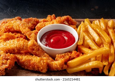 Chicken Tenders , Crispy Boneless Meat Pieces With A Red Dip And French Fries, On A Black Background With A Place For Text