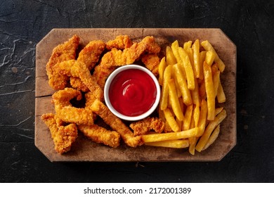 Chicken Tenders, Crispy Boneless Meat Pieces, With A Red Dip And French Fries, Overhead Flat Lay Shot On A Black Slate Background