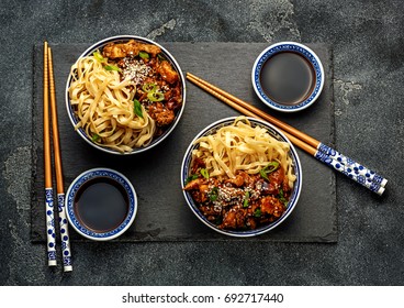 Chicken teriyaki on dark background  and sesame seeds. Asian food. Noodles and soy sauce. Top view. - Shutterstock ID 692717440