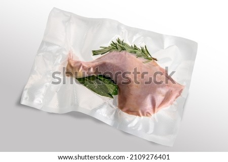 Chicken thigh in vacuum packed sealed for sous vide cooking with rosemary, bay leaf and sage, isolated on white