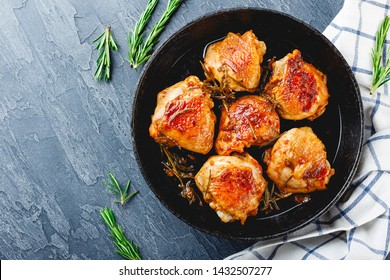 Chicken Thighs Fried With Rosemary In A Cast Iron Skillet And Rosemary On Background, View From Above