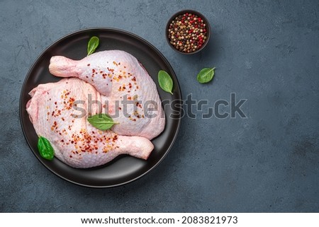 Chicken thighs in a plate on a dark background with spices and basil. Top view, copy space. Cooking.