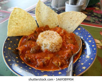                 Chicken Tiki Masala in a bowl with rice, tortilla chips and spoon              