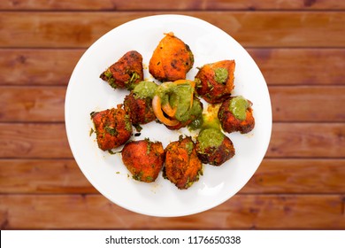 "Chicken Tikka" - an Indian dish or cuisine prepared with barbecued chicken pieces  served as a starter or breakfast  also ideal filler in drinks party clicked on a wooden plank background