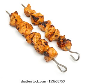 Chicken tikka kebabs on metal skewers.