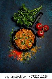 Chicken Tikka Masala In A Cast-iron Pan, Vegetables On A Blue Background. View From Above