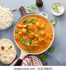 Chicken tikka masala, cooked marinated chicken chunks in spiced curry sauce, served with rice and naan bread top view in a skillet with copy space