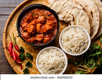 Chicken tikka masala spicy curry meat food in cast iron pot with rice and naan bread close up