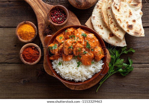 Chicken tikka masala
spicy curry meat food in a clay plate with rice and naan bread on
wooden background.