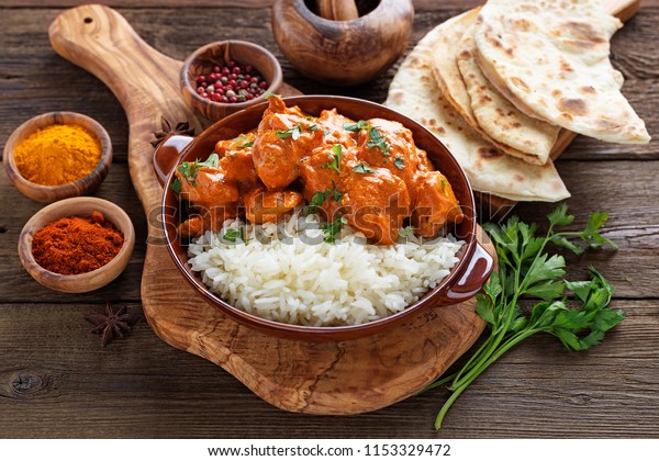 Chicken tikka masala\
spicy curry meat food in a clay plate with rice and naan bread on\
wooden background.