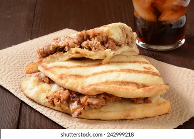 A chicken tikka sandwich on naan bread with a soft drink