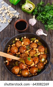 Chicken Or Turkey Meatballs Smothered In Sauce Of Green Bell Pepper, Onion, Soy Sauce, Chinese Cooking Wine And Spices In Pan, Ingredients On Wooden Background Close-up, Vertical View From Above