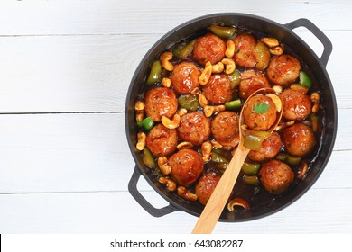 Chicken Or Turkey Meatballs Smothered In Sauce Of Green Bell Pepper, Onion, Soy Sauce, Chinese Cooking Wine And Spices In Pan On White Wooden Table, View From Above