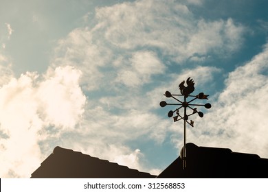 Chicken Weather Vane On A Roof With Blue Sky.