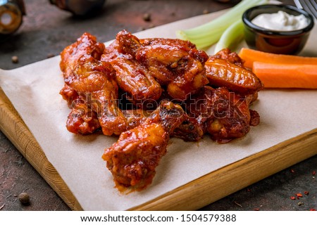 chicken wings in barbecue sauce and with blue cheese sause on dark rustic concrete table