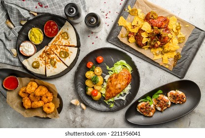 Chicken Wings In Barbecue Sauce , Chicken Breast, Quesadilla With Chicken, Cheese Balls, Bruschetta With Tomatoes And Cheese Top View On Grey Table