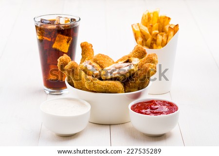 Chicken wings, french fries, coke and sauces on the table