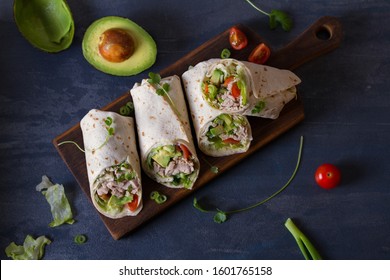 Chicken wraps with avocado, tomatoes and iceberg lettuce. Tortilla, burritos, sandwiches, twisted rolls. View from above, top