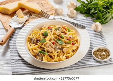 Chicken-Pepper Mushroom Alfredo linguine sprinkled with fresh sage leaves in white bowl on white wood table with ingredients at background, horizontal view from above - Powered by Shutterstock