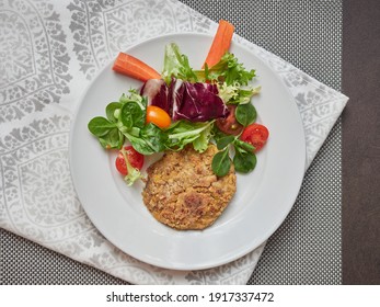 Chickpea Veggie Burger And Salad On A White Plate On A Gray Tablecloth And Napkin, View From Above