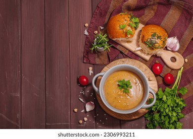 Chickpea-tomato cream soup with fragrant garlic buns. Comfort food, nostalgic mood concept, healthy vegan lunch. Wooden background, flat lay, top view